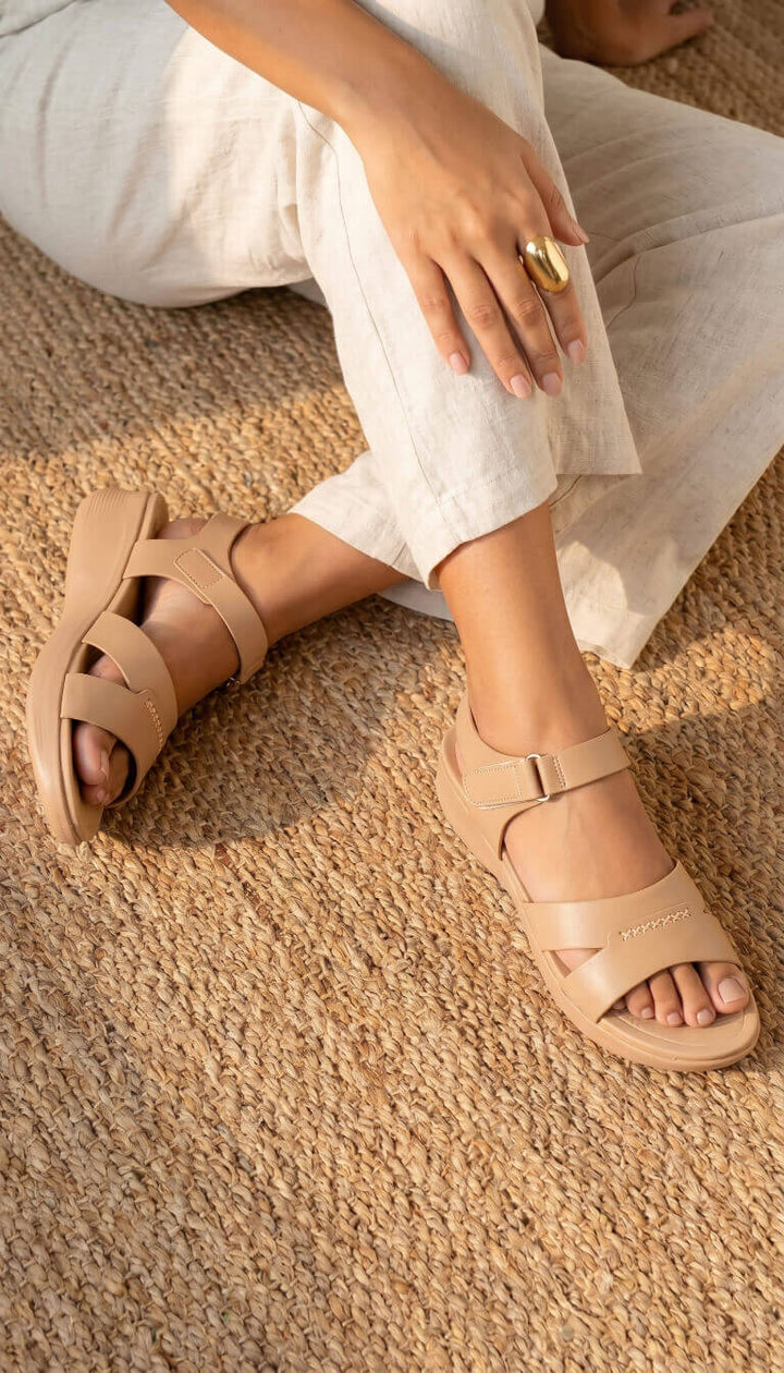Person wearing beige sandals on a textured surface